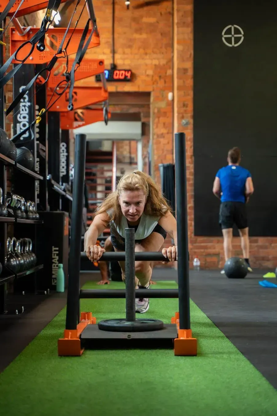 Member pushing a sled across the turf in a HIIT class at HIIT West Hampstead