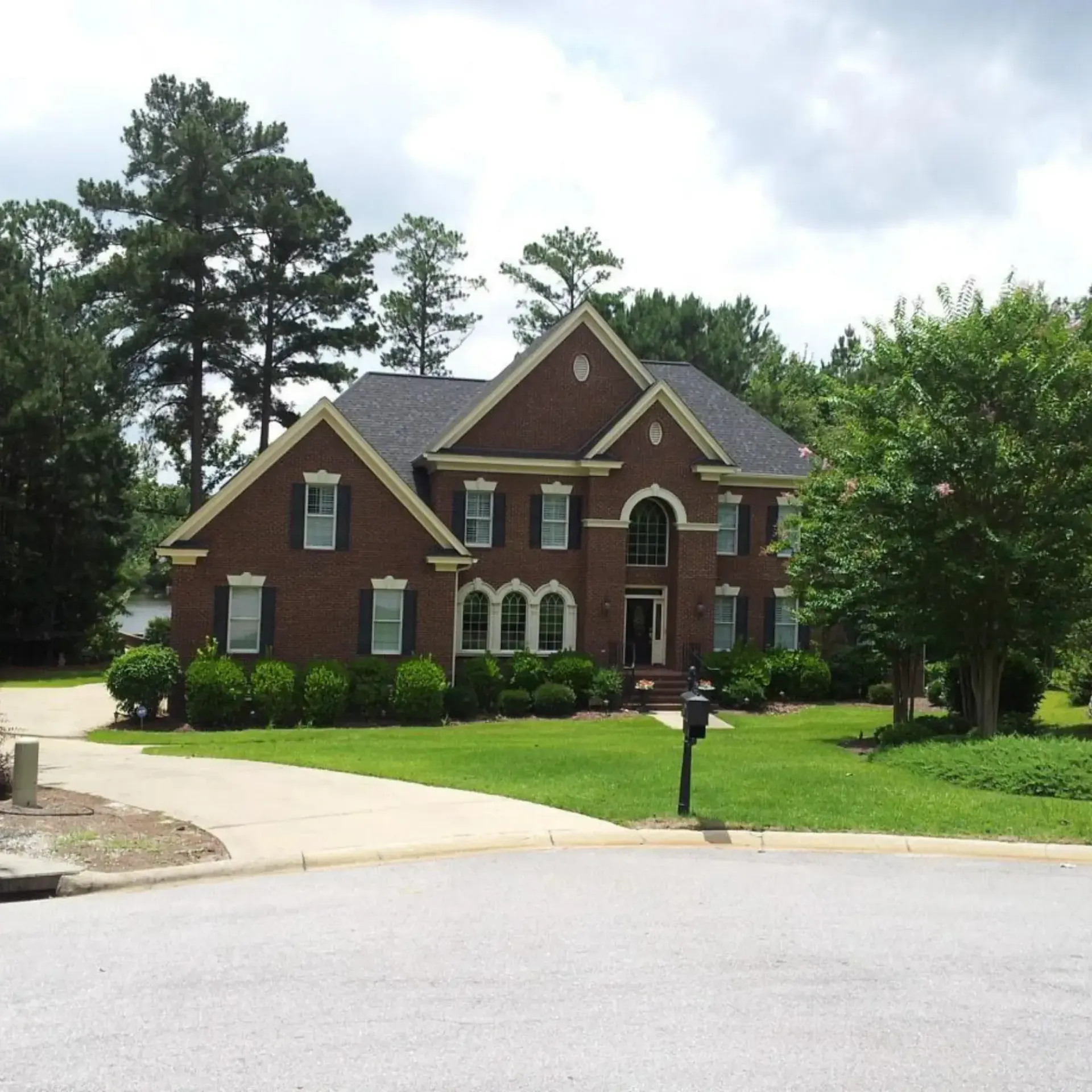Honey Badger Lawn & Landscape -
A large brick house with a mailbox in front of it.