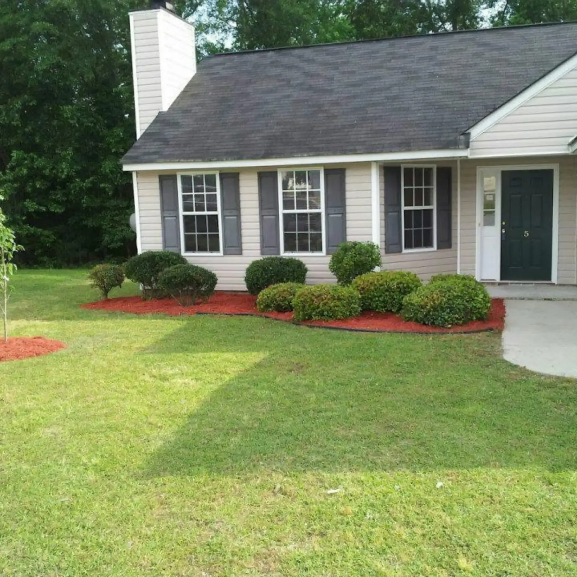 Honey Badger Lawn & Landscape - A white house with a black roof and shutters