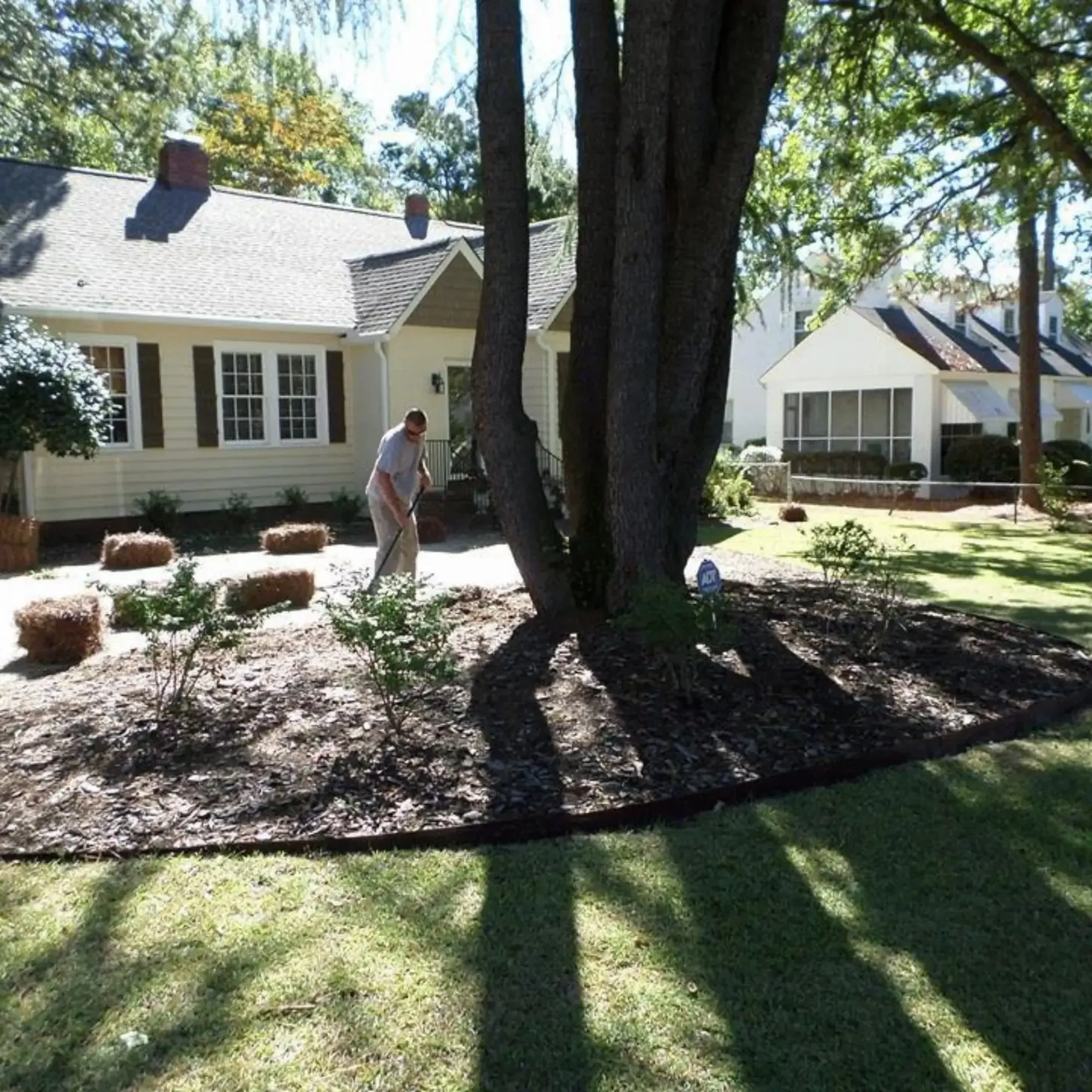 Honey Badger Lawn & Landscape - A man standing in front of a house with a shovel in his hand
