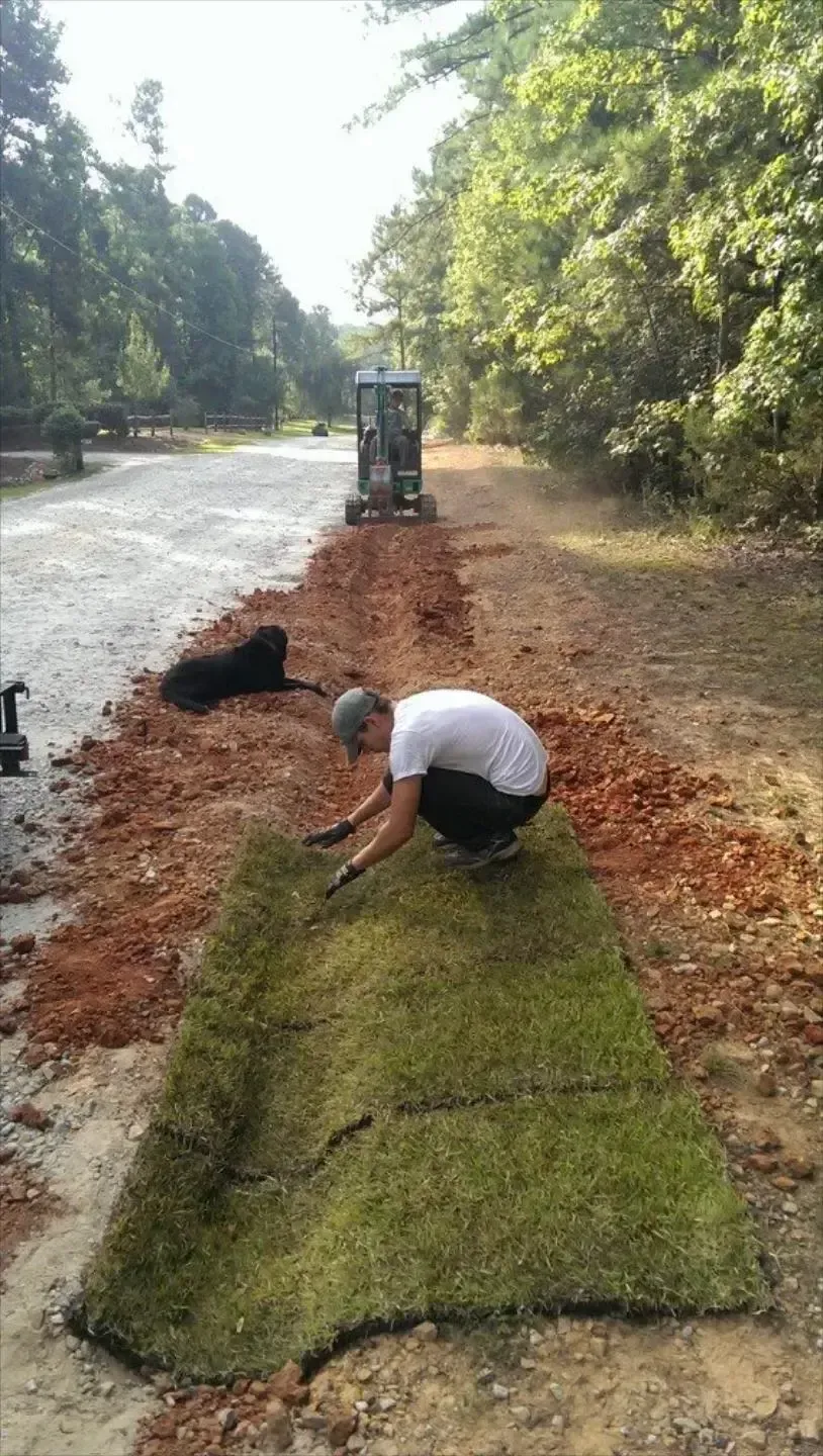 Honey Badger Lawn & Landscape
- A man is kneeling down next to a large piece of grass.
