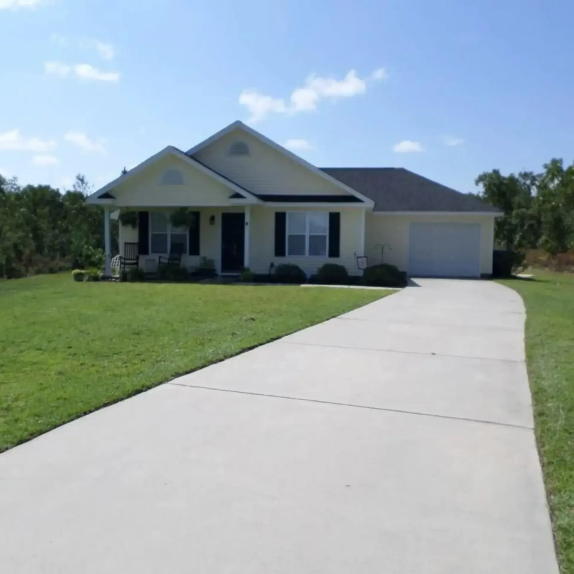 Honey Badger Lawn & Landscape - 
A white house with a concrete driveway leading to it