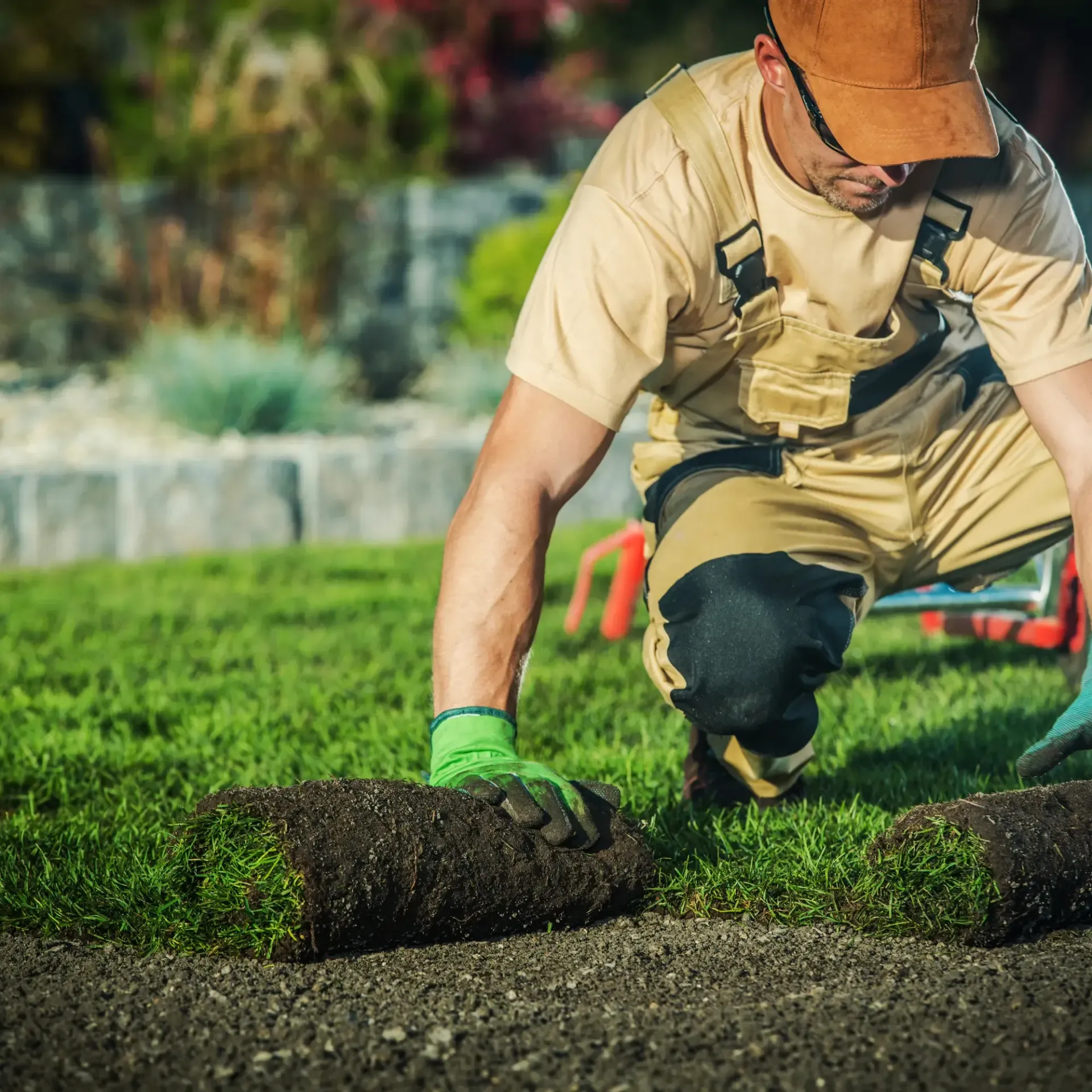 Honey Badger Lawn & Landscape -  A man is laying a roll of grass on the ground.
