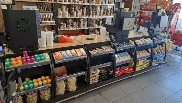 קופה בחנות, עם תצוגות צבעוניות של ממתקים ומדפי חטיפים בחנות קמעונאית
