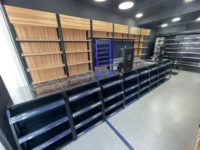 חלל פנים של חנות קמעונאית ריקה, עם דלפקים שחורים ומדפי עץ לאורך הקירות