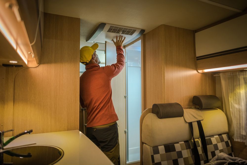 Man in Caravan Reaching Towards Ceiling Inspecting the AC — Auto Marvel In Mount Saint John, QLD