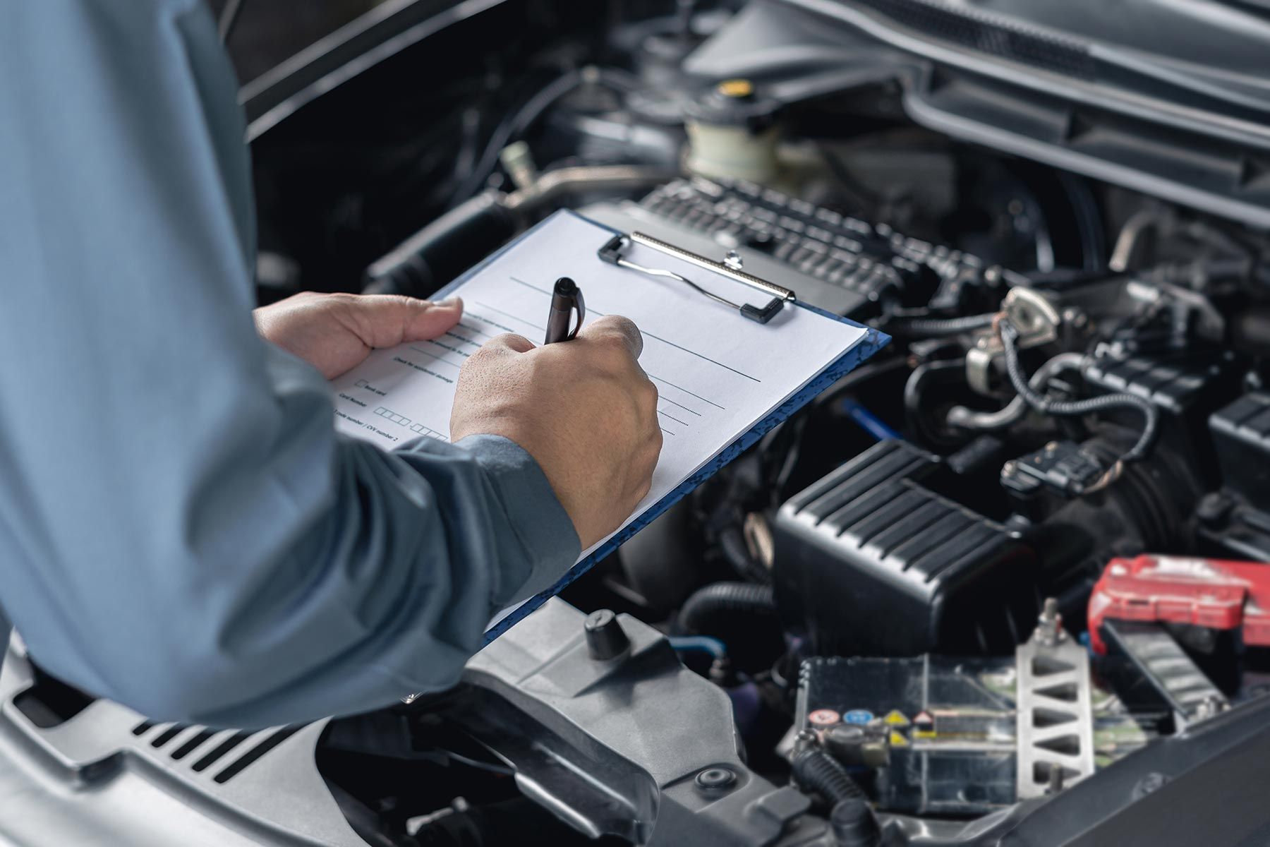 A Mechanic is Writing on a Clipboard While Working on a Car — Auto Marvel in Townsville, QLD