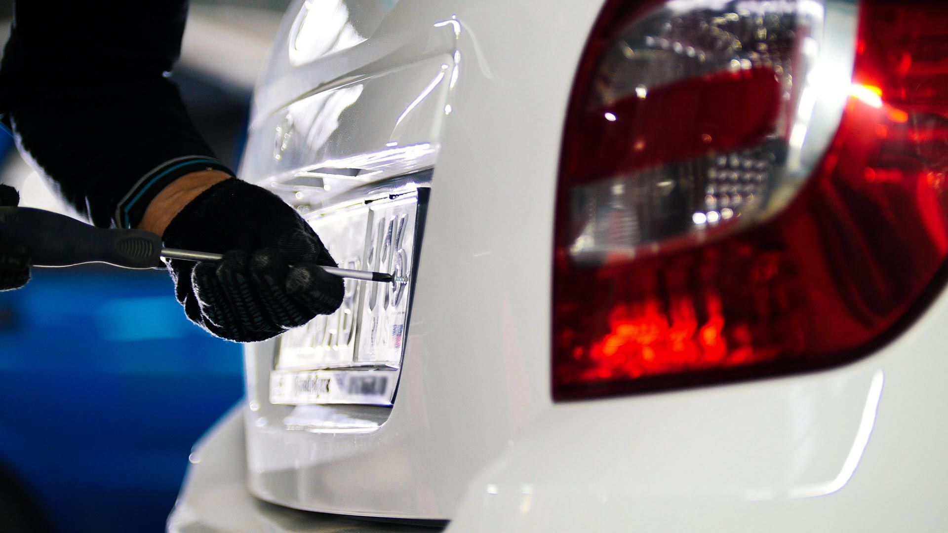 Gloved Hand Installing a License Plate on the Rear of a White Caravan — Auto Marvel in Townsville, QLD
