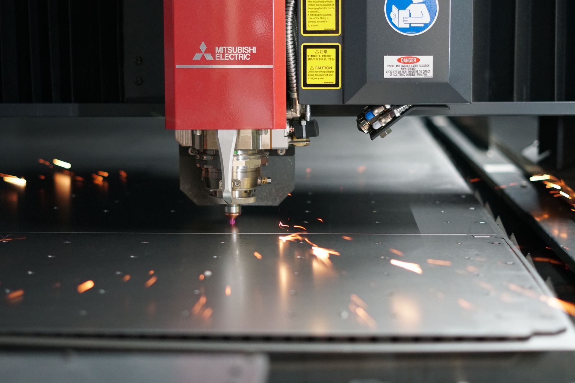 Laser cutting metal sheet, red sparks fly. Mitsubishi laser cutter in action.