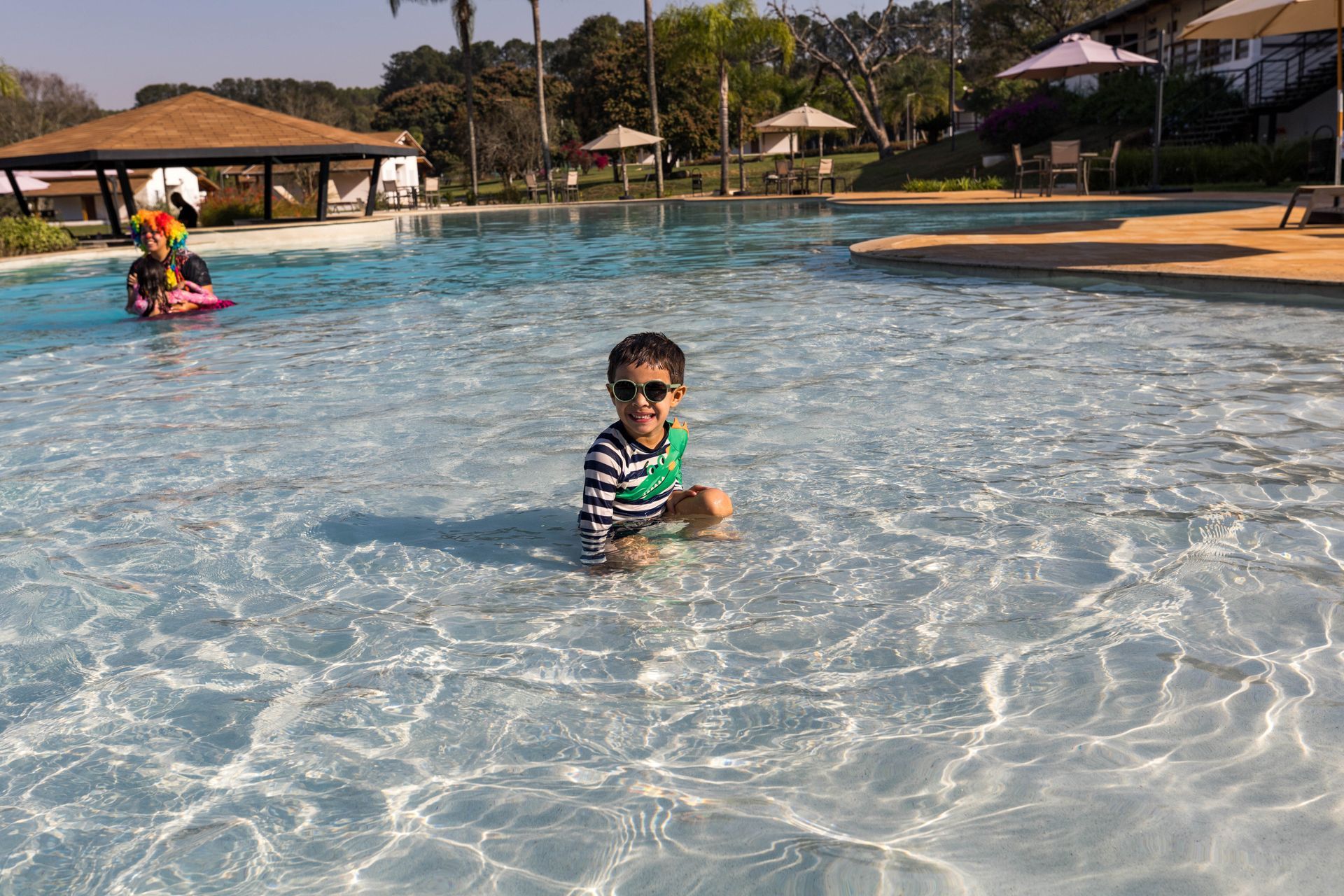 Um menino está sentado em uma grande piscina.