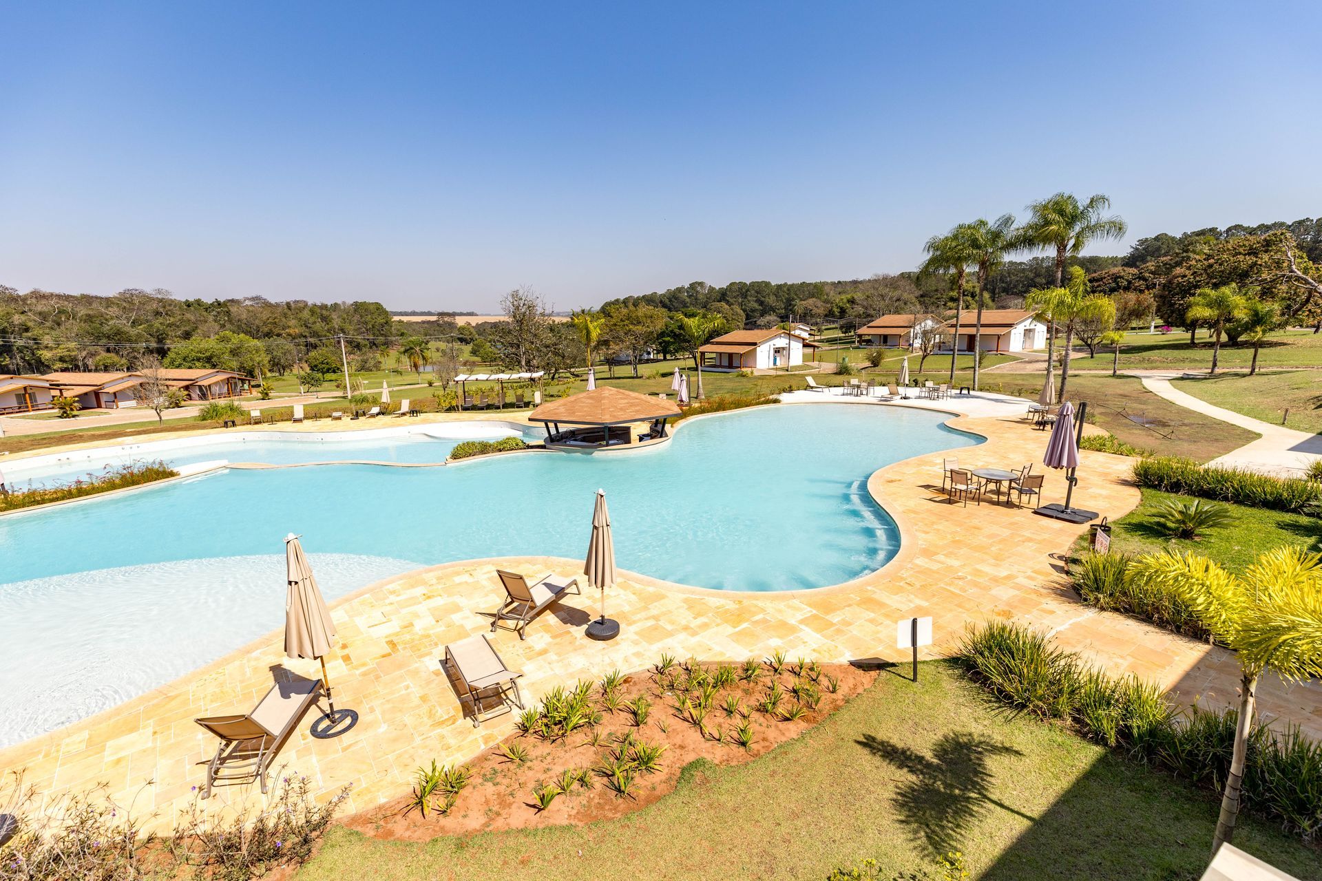 Uma vista aérea de uma grande piscina cercada por cadeiras e guarda-sóis.