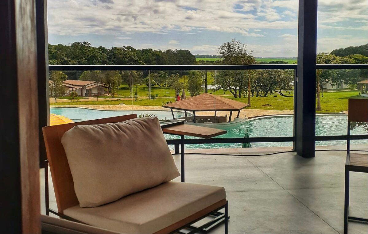 Uma cadeira está em uma varanda com vista para uma piscina.