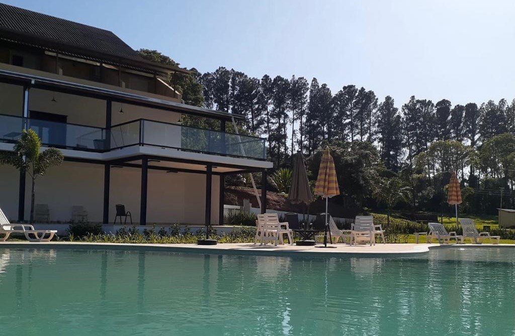 Uma grande piscina com cadeiras e guarda-sóis em frente a uma casa
