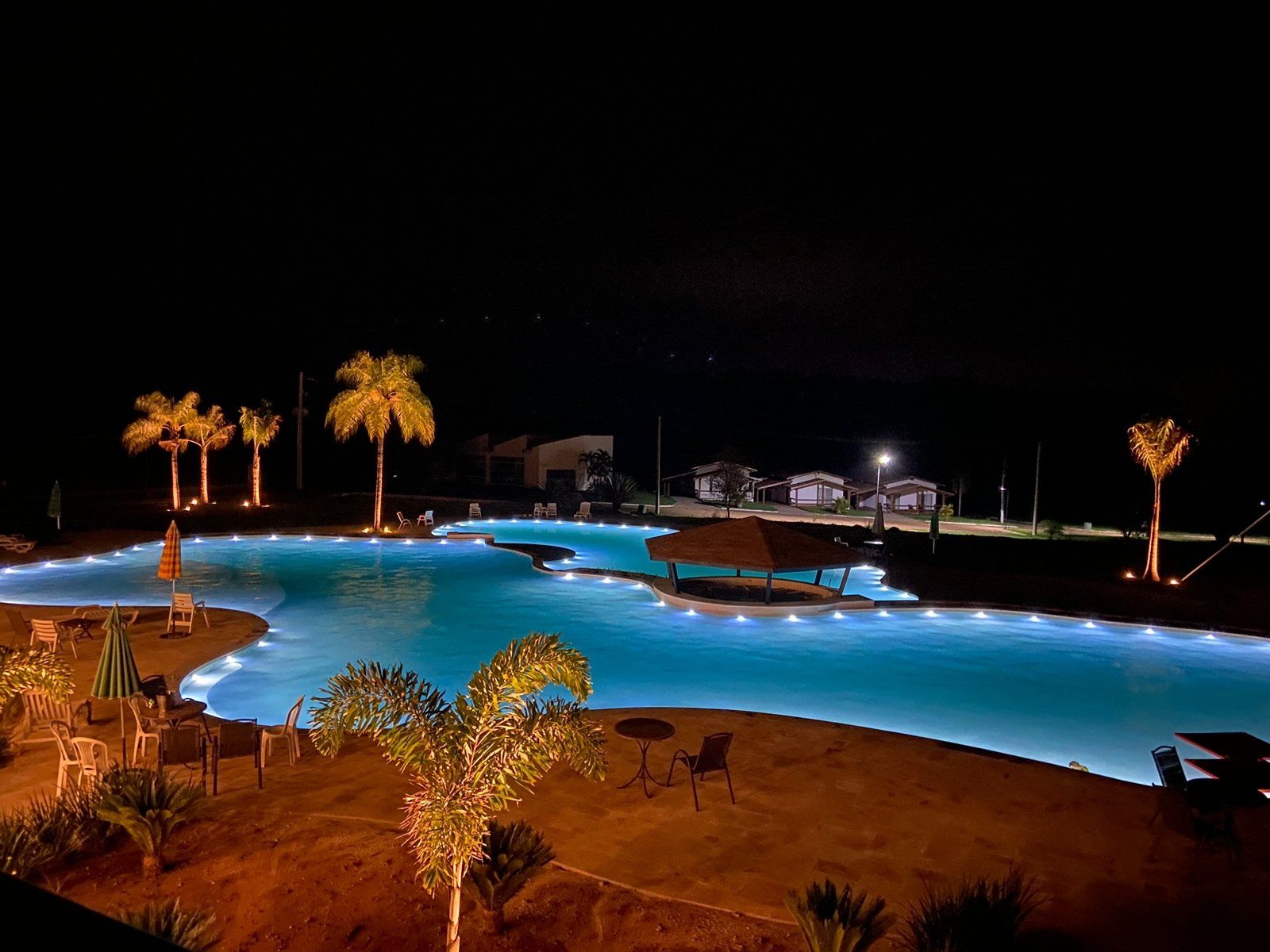 Uma grande piscina é iluminada à noite