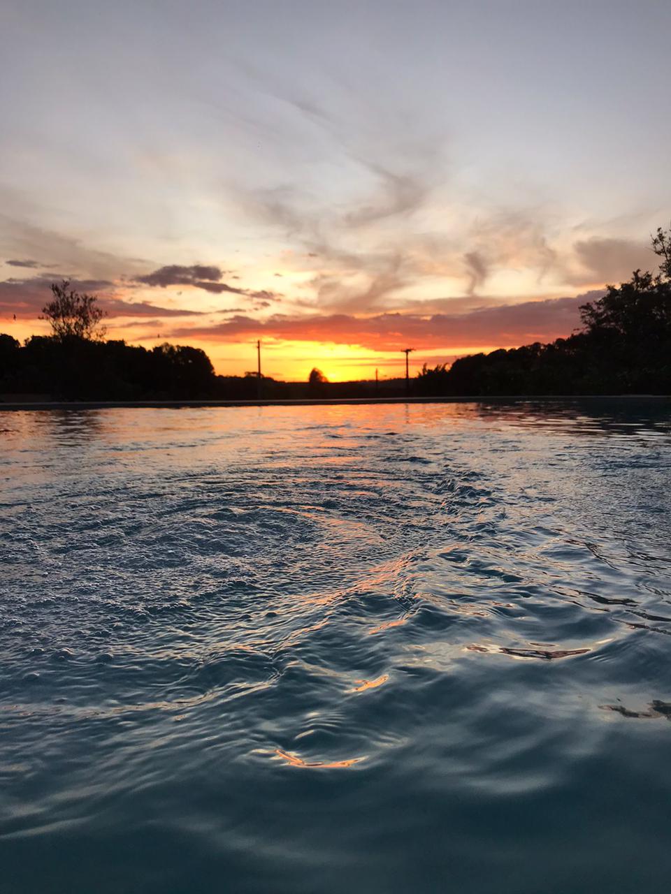 Um pôr do sol sobre um corpo d'água com árvores ao fundo.