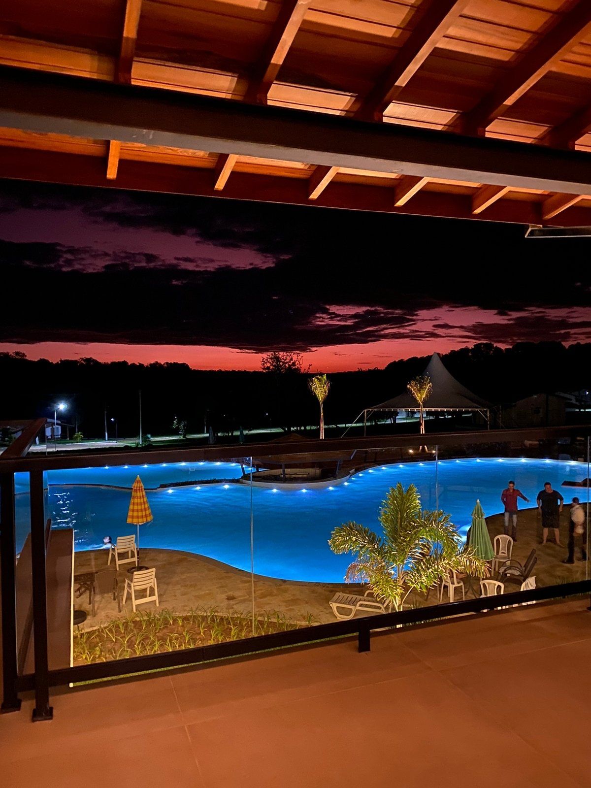 Uma vista de uma piscina à noite de uma varanda