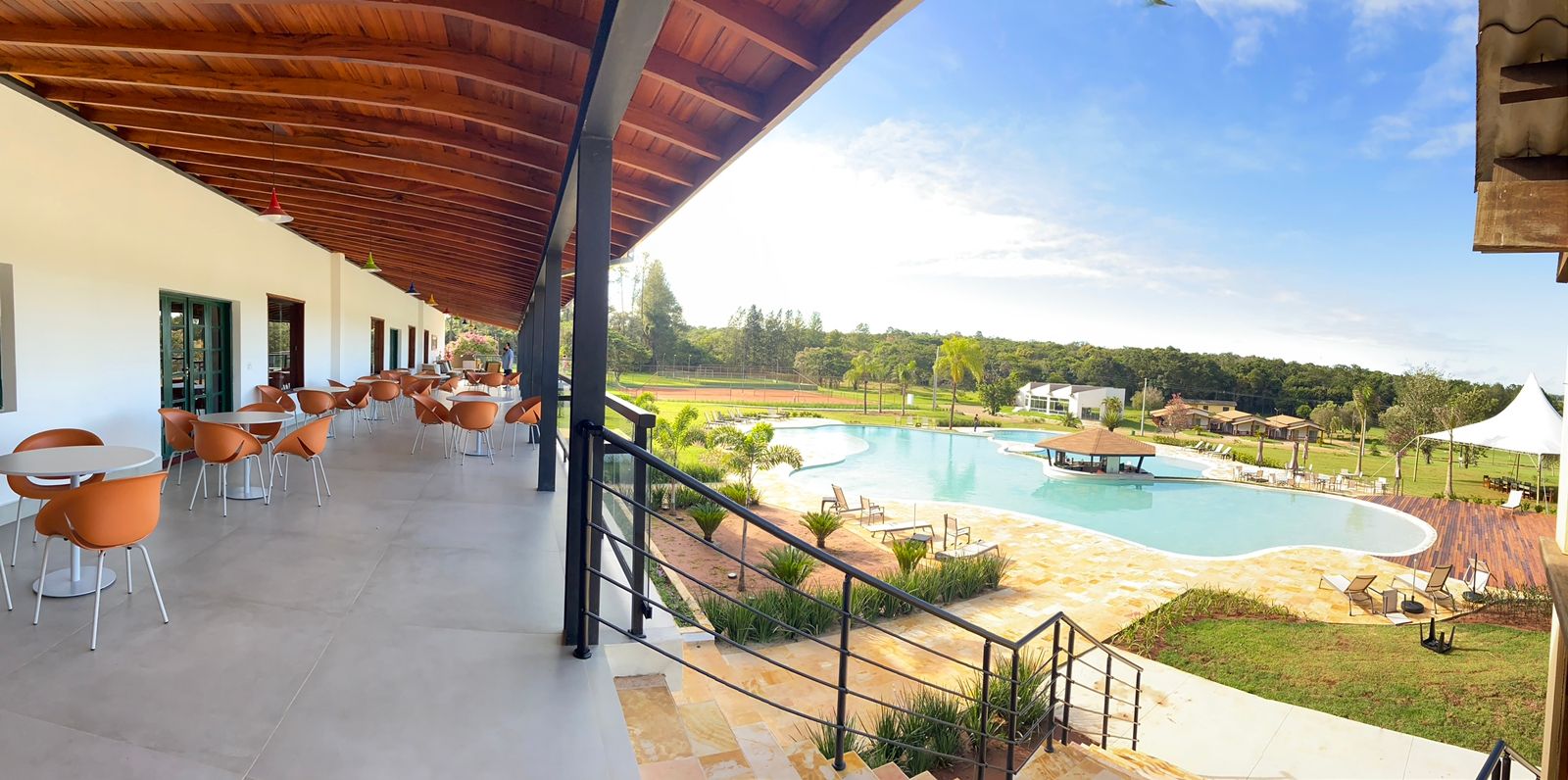 Um grande pátio com mesas e cadeiras com vista para uma grande piscina.