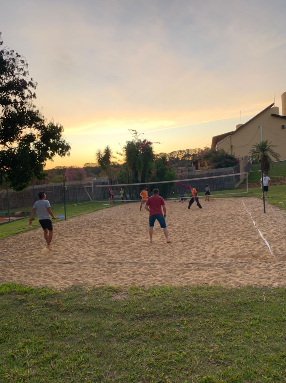 Um grupo de pessoas está jogando vôlei em uma quadra de areia.