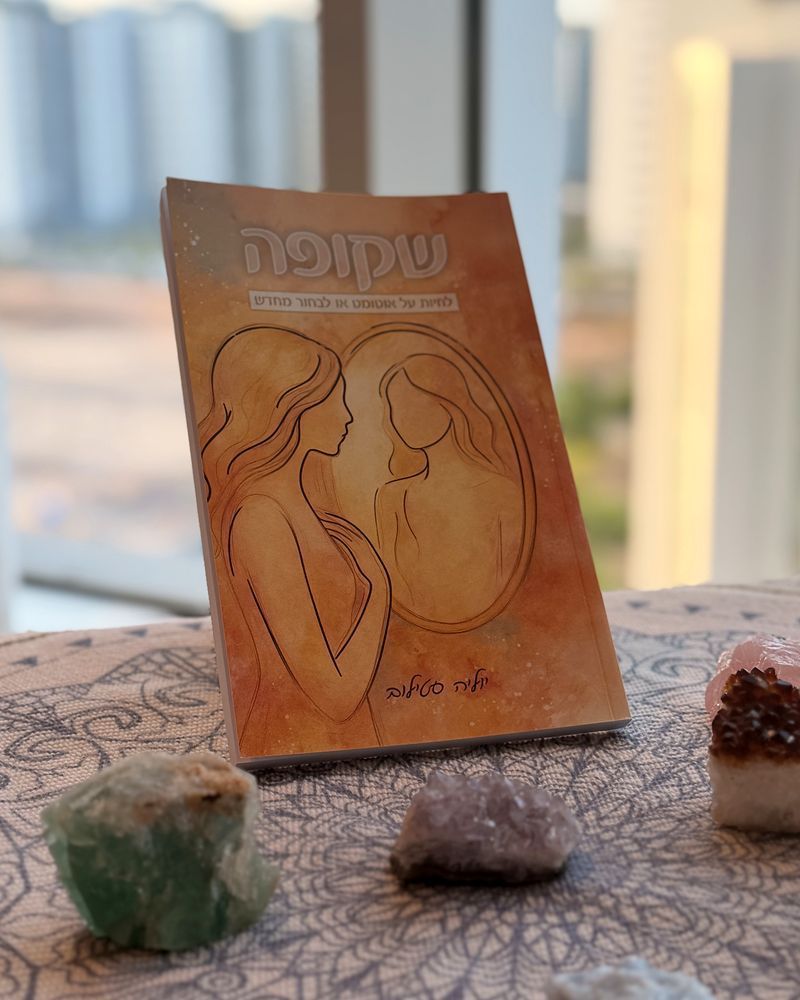 הספר שקופה עומד על מפת מנדלה, מוקף באבני קריסטל, מול חלון
