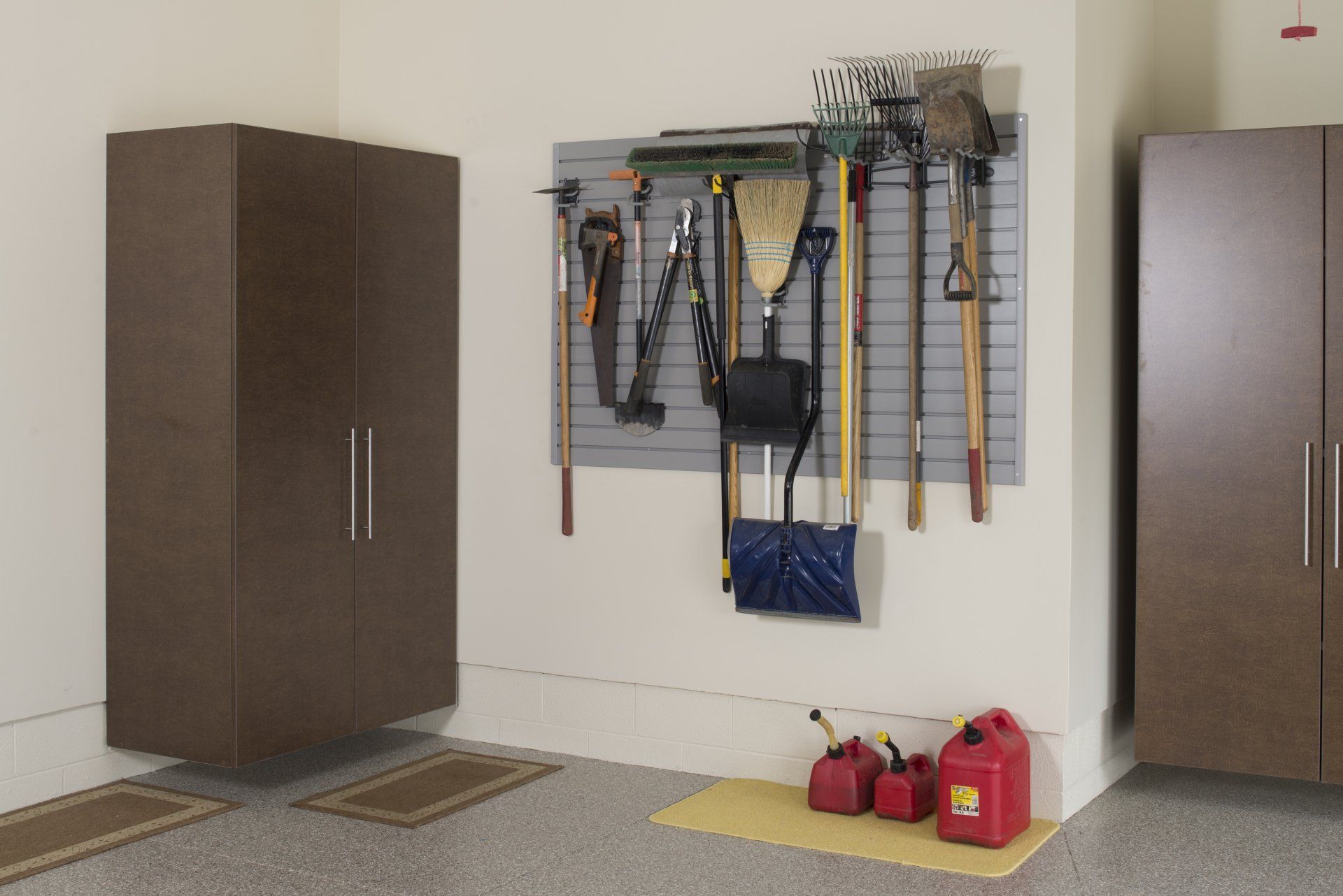 Garage with storage cabinets, wall-mounted tools, and gas cans.
