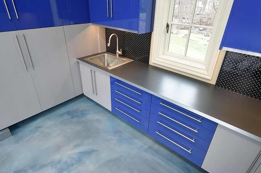 Blue and gray utility room with cabinets, sink, and metallic countertop; blue-painted floor.