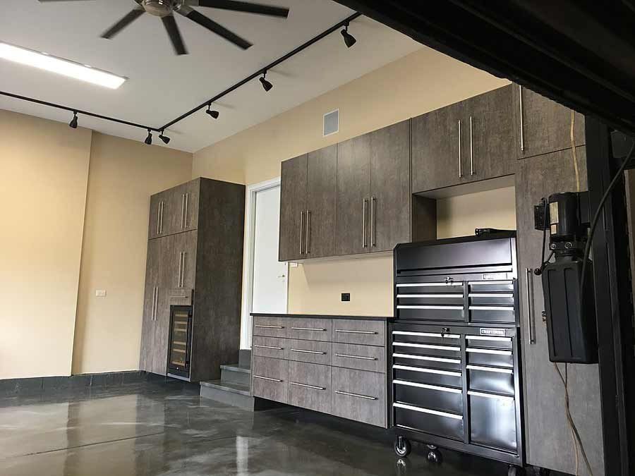 Garage interior with gray cabinets, a large toolbox, and shiny concrete floor.