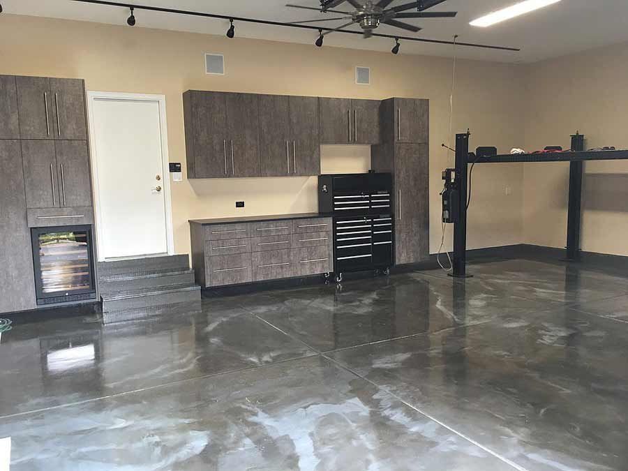 Garage interior with cabinets, tool chest, car lift, and epoxy flooring.
