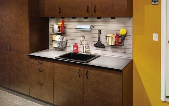 Brown cabinets and countertop with a sink and storage rack in a utility room.