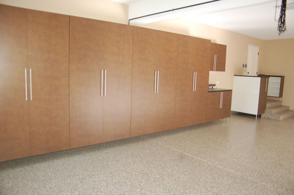 Garage with light brown storage cabinets and speckled floor.