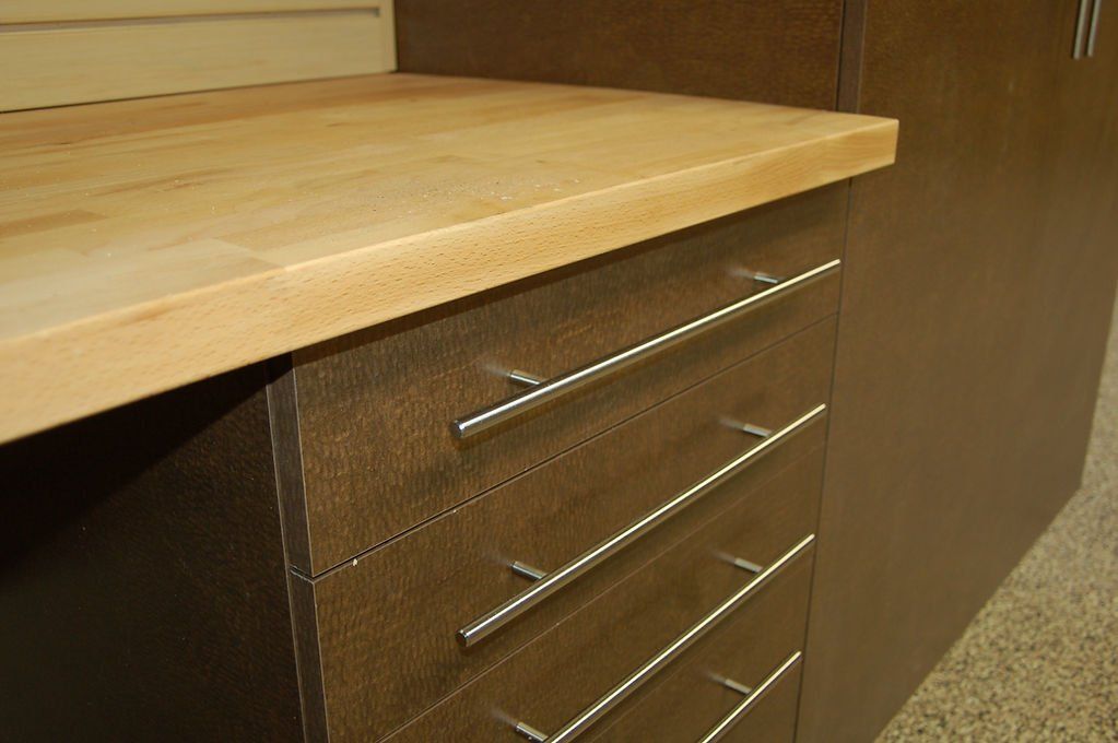 Wooden countertop over dark brown drawers with metal handles.