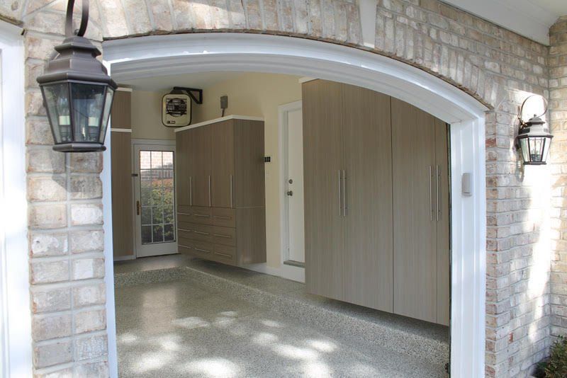 Garage interior with storage cabinets, finished floor, and outdoor lighting fixtures.