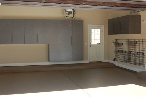 Garage interior with grey cabinets, white door, and wire rack on a beige wall.