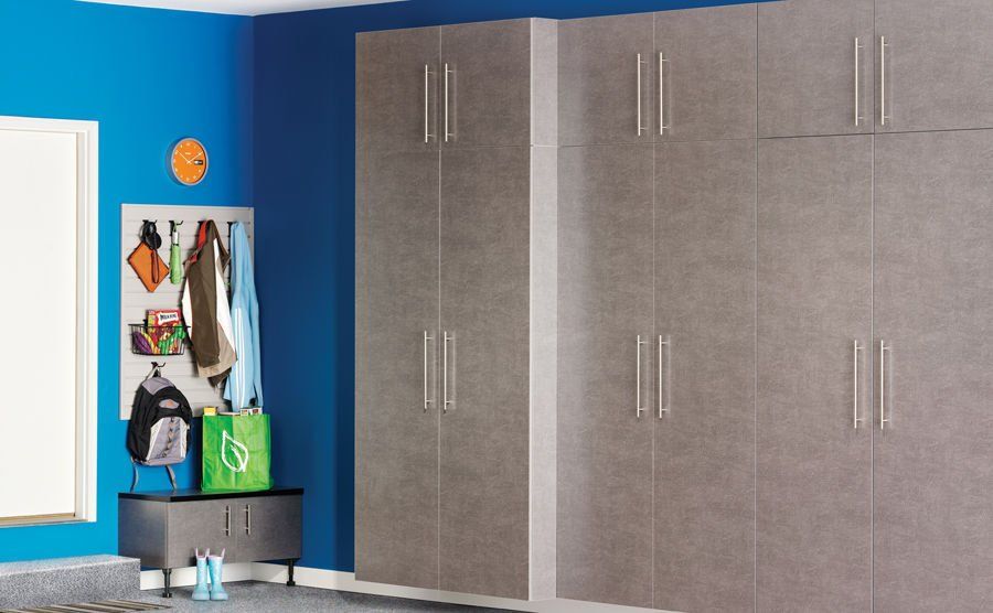 Gray storage cabinets in a garage with a blue wall. A coat rack and a storage bench are also present.