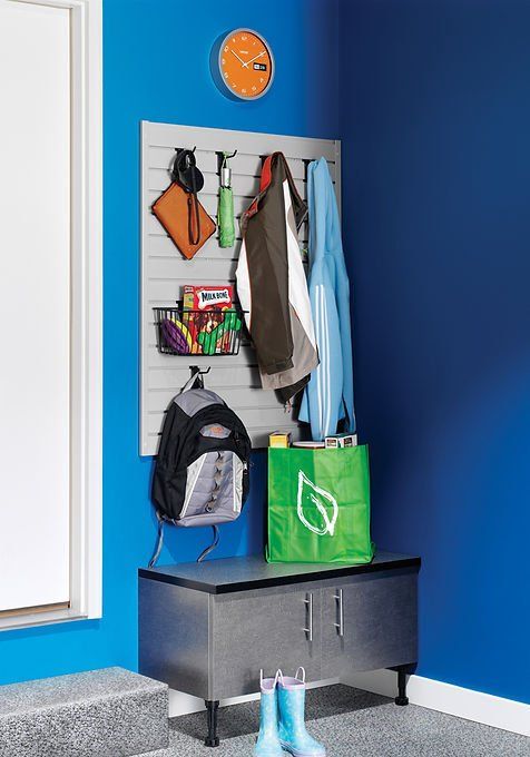Storage area: gray panel with hooks, bench, and various items like coats, backpack, and boots against a blue wall.