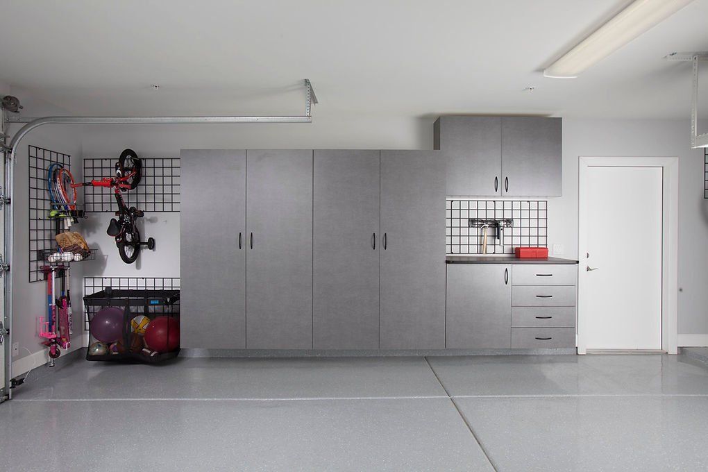 Garage with gray cabinets, storage, and organized items on walls.