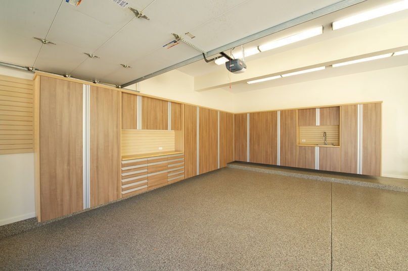 Garage interior with light wood cabinets, drawers, and speckled floor.