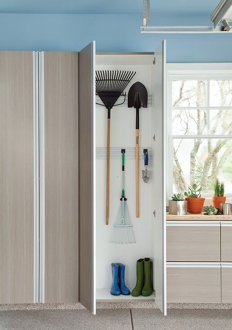 Garage storage cabinet with gardening tools, boots, and window in background.