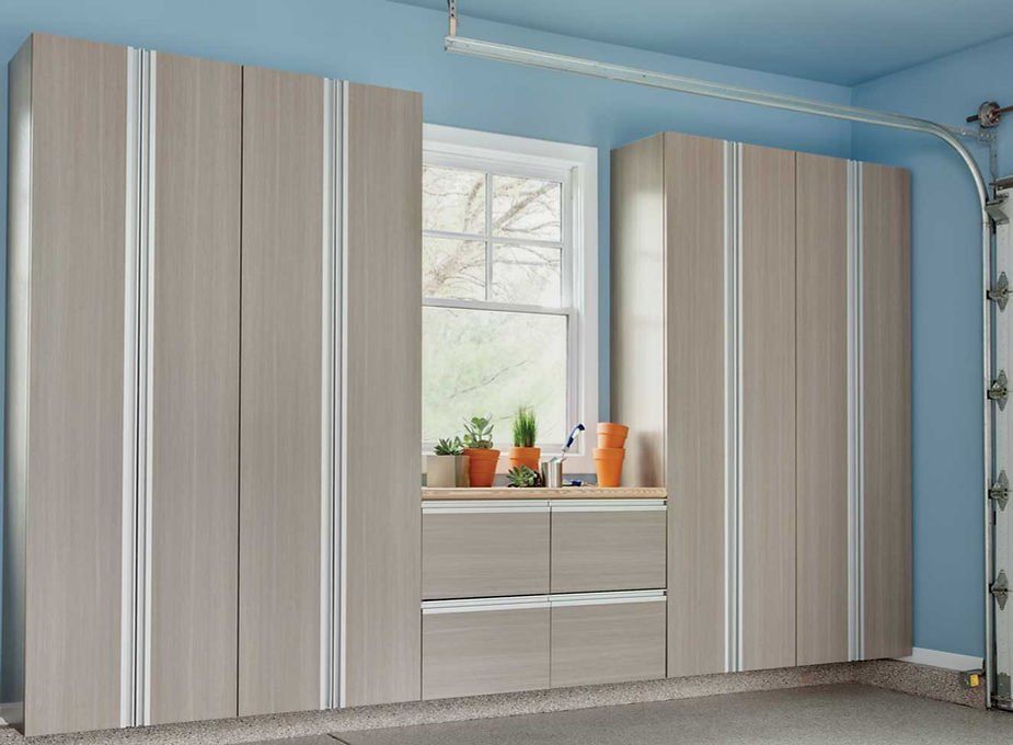 Garage cabinets with a window, in beige and white, with a blue wall.