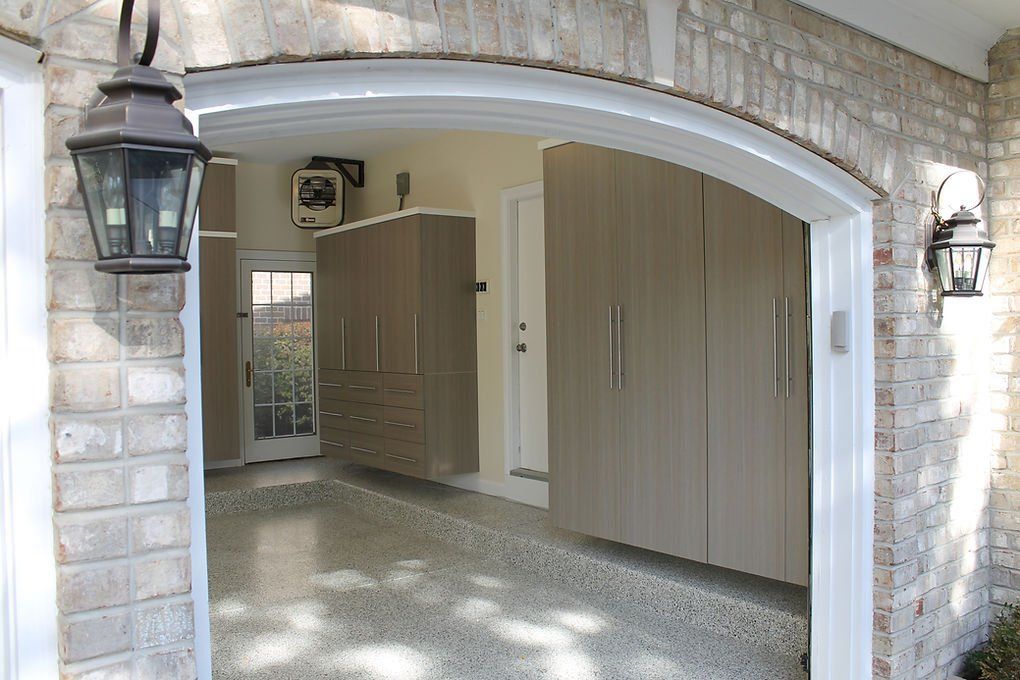 Garage with cabinets, epoxy floor, and arched entryway. Beige and gray color scheme.