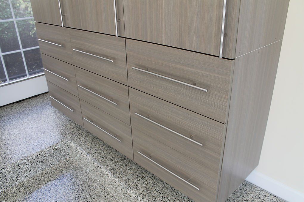 Wooden cabinets with drawers and doors, silver handles, against a wall next to a window.