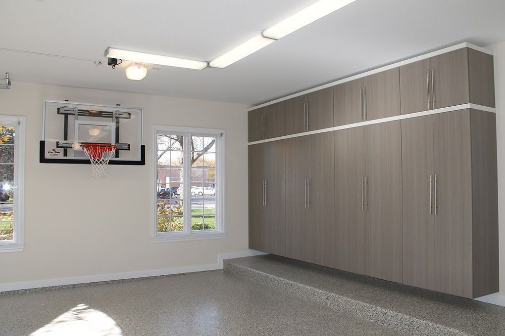 Garage with storage cabinets, basketball hoop, and windows; neutral tones.
