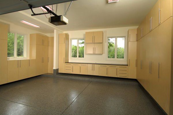 Well-organized beige garage with cabinets and a dark gray floor.