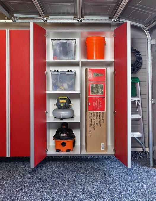 Red and white storage cabinets in a garage, holding bins, tools, and a boxed item.