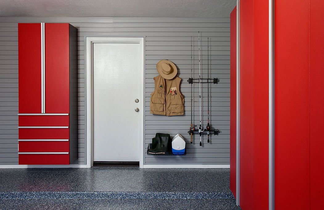 Garage with red cabinets, white door, and gray wall with fishing gear.