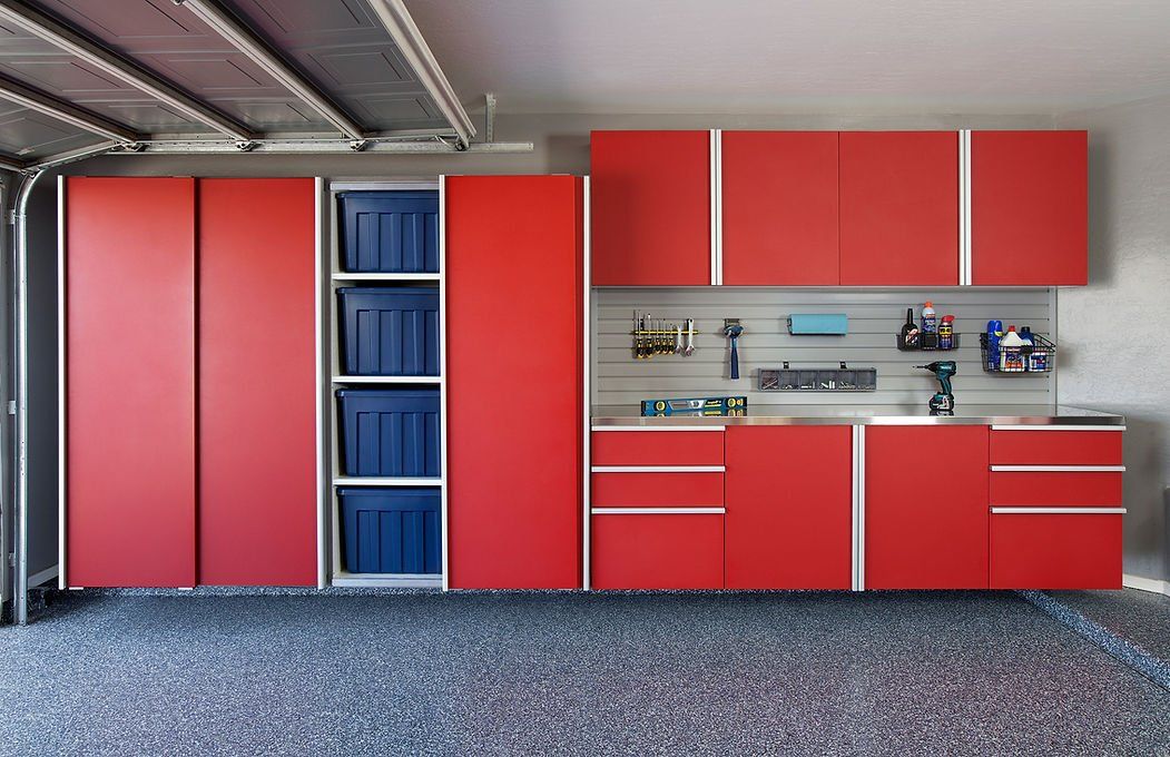 Red garage cabinets with silver trim, holding tools and storage bins, against a gray wall.