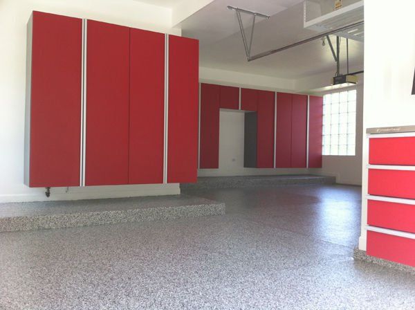 Garage interior with red cabinets and speckled floor.