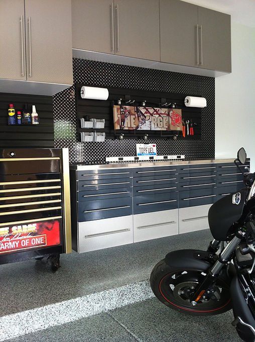 Garage workspace with cabinets, tool chest, pegboard, and motorcycle.