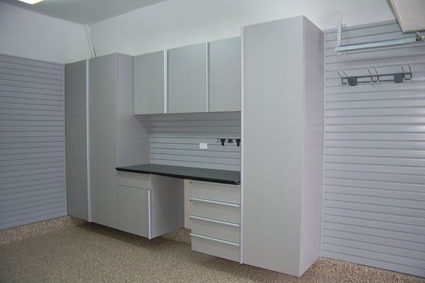 Gray garage cabinets and workbench against a gray slatwall, in a garage.