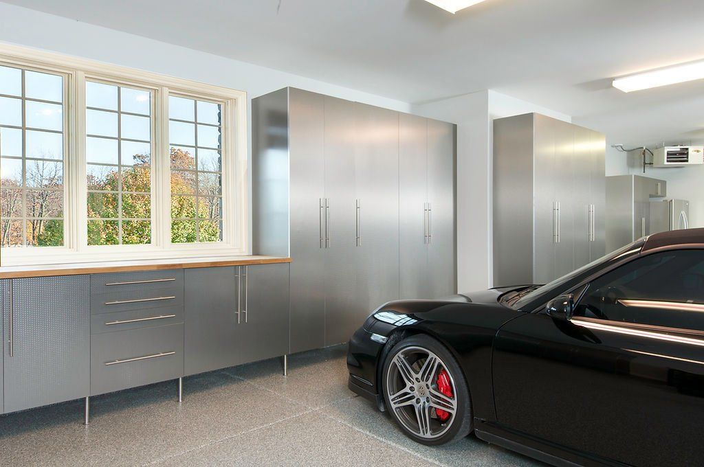 Sleek garage with black sports car, stainless steel cabinets, and a window with a view.