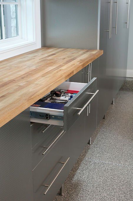 Metal cabinets with wood countertop. One drawer open, filled with tools.